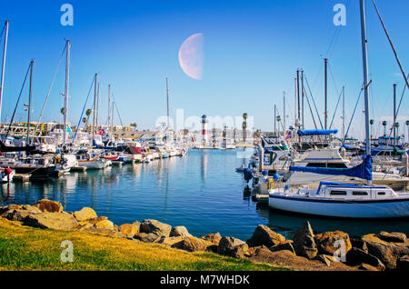 Hafen, Mond, Boote, Tageslicht, blaue Wasser, Leuchtturm, Felsen und grünen Gras. Stockfoto