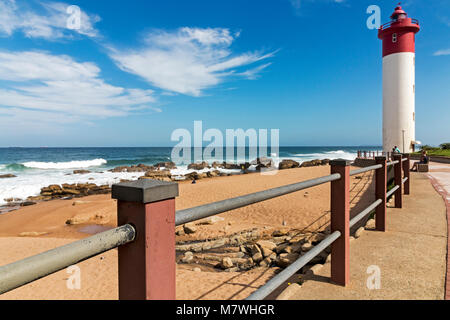 Gehweg mit Metall Barriere gegen rot-weiße Leuchtturm gegen den blauen bewölkt Coastal Marine in Umhlanga, Durban, Südafrika Stockfoto