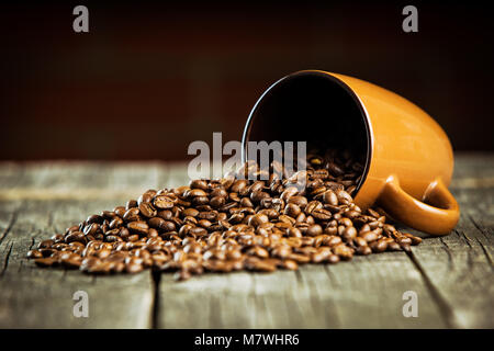 Kaffeebohnen und Kaffeetasse auf Holztisch. Stockfoto