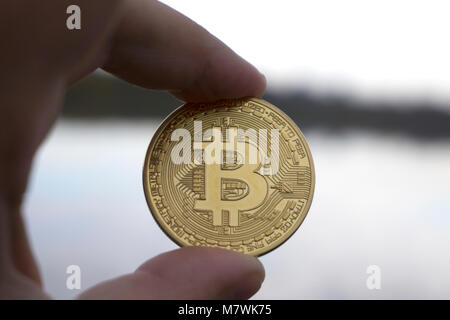 Hand hält ein gold Bitcoin im Hintergrund Stockfoto