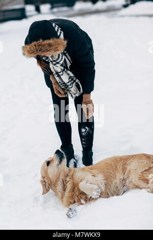 Bild von Mädchen in schwarzen Jacke mit Retriever auf Spaziergang im Winter Park Stockfoto