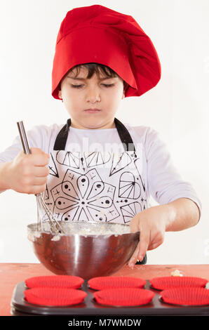 Süße kleine Kleidung Koch junge Cupcakes vorbereiten Stockfoto