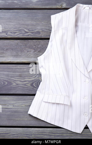 In der Nähe von Weißen ärmellosen business Jacke. Vertikale Ansicht, Schreibtisch aus Holz Oberfläche Hintergrund. Stockfoto