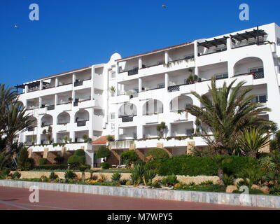 AGADIR, Marokko im Februar 2017: Weißes modernes Gebäude und Palmen in Schönheit Sitzgelegenheiten im Freien Plätze am Strand am Meer in Stadt und klare Stockfoto