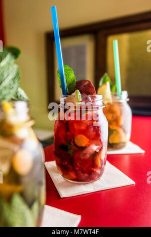 Hausgemachte Limonade Eistee bunte Icetea trinken mit frischen süßen Früchten Minze im Glas auf den Felsen mit einem Strohhalm Stockfoto