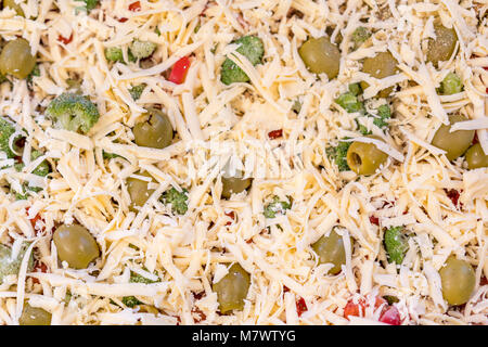 Die Pizza vor dem Backen. Hintergrund der geriebenen Käse Stockfoto