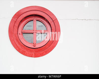 Die alte runde rote Fenster in eine weiße Wand Stockfoto