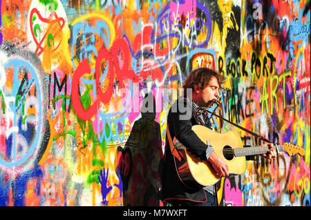 Straße Gaukler führt Beatles Musik an der John Lennon Mauer an der Kampa Insel. in Prag. Musiker mit Gitarre vor bunten Graffiti an der Wand Stockfoto