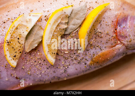 Rohe frische Lachs, gewürzt mit Zitrone und Gewürze, Gurke. Auf hölzernen Schneidebrett Stockfoto