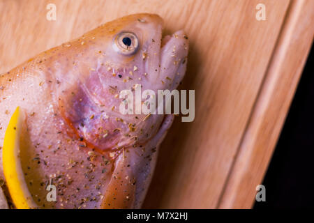 Rohe frische Lachs, gewürzt mit Zitrone und Gewürze, Gurke. Auf hölzernen Schneidebrett Stockfoto