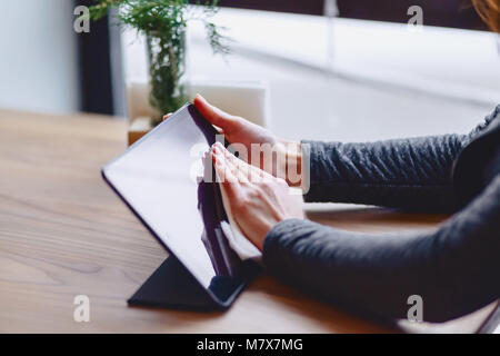 Das Mädchen in der Brille wischt die Tablet Bildschirm am Tisch im Cafe closup Stockfoto