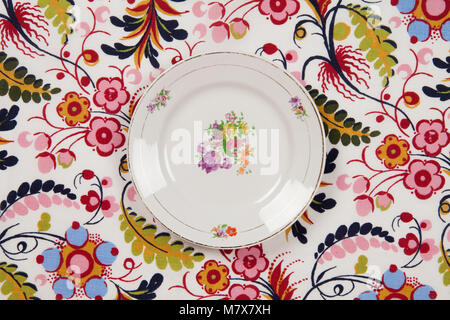 Eine Blume, die Platte auf einem geblümten Stoff versteckt. Camouflage Spiel. Minimale Farbe still life Fotografie. Stockfoto
