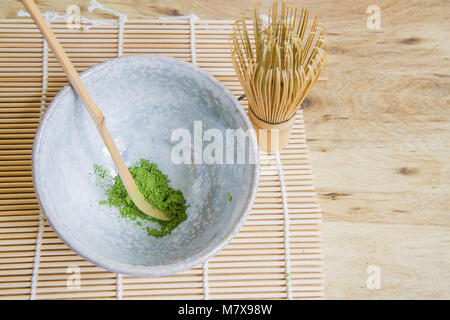 Oben Blick auf Japanische Tee Zeremonie Elemente einschließlich einen Stein Schale Matcha Grüntee Pulver, ein bambusbesen und Bambus Schaufel auf ein Bambus Matte. Stockfoto