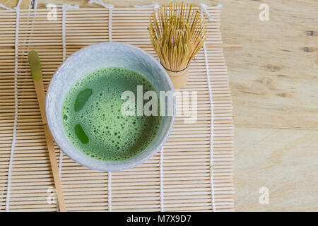 Oben Blick auf Japanische Tee Zeremonie Elemente einschließlich einen Stein Schüssel mit Matcha grüner Tee, bambusbesen und Bambus Schaufel auf ein Bambus Matte. Stockfoto