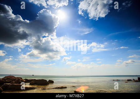 Flache transparent gelb steinigen Meeresgrund unter Ebbe gegen azurblauen Meer und blauen bewölkten Himmel Stockfoto