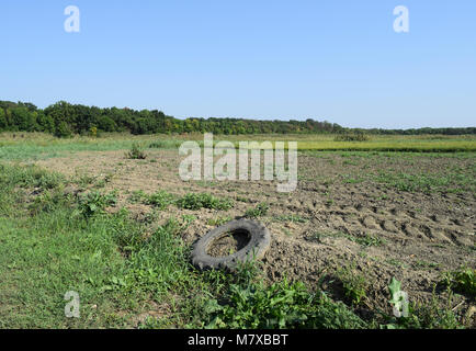 Das alte Rad protector liegt am Rande eines gepflügten Feldes. Stockfoto