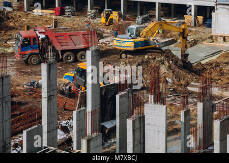 Maschinen und Bulldozer mit Boden- und Strahl in Gebäude contstruction Website auf dem Hintergrund der schmutzigen Boden. Industrielle Landschaft mit Gebäude arbeiten Stockfoto