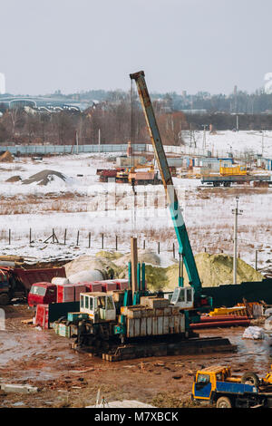 Kranausleger Maschinen und Bulldozer auf den Aufbau Baustelle auf dem Hintergrund der schmutzigen Boden. Industrielle Landschaft mit Kränen und Gebäude, und wor Stockfoto