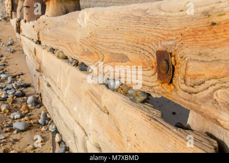 Kiefer groyne mit Kieselsteinen, die Lücken durch die Kraft der Wellen blockiert, am Strand in Bexhill-on-Sea, East Sussex, England Stockfoto