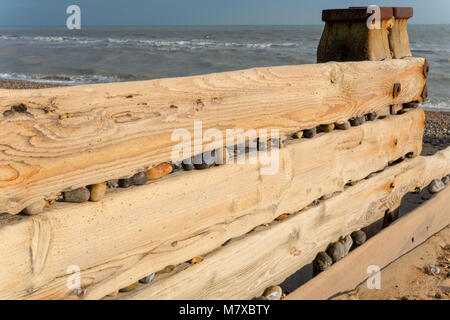 Kiefer groyne mit Kieselsteinen, die Lücken durch die Kraft der Wellen blockiert, am Strand in Bexhill-on-Sea, East Sussex, England Stockfoto