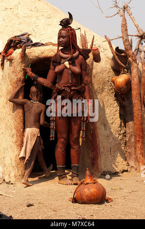 Frau Himba vor seiner Hütte in seinem Dorf in der Nähe von Epupa Falls. Himbas sind normalerweise gefunden in der Nähe der Wasserfälle und in den Dörfern in der Umgebung, Namibia Stockfoto