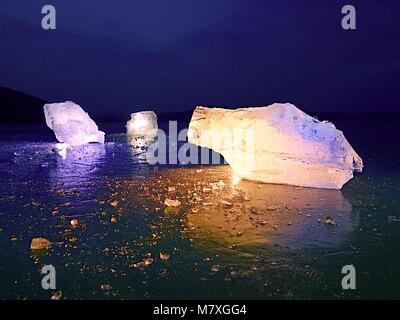 Shining faltige Oberfläche gebrochenem Eis, frische eisige Stücke auf flachen frost Boden. Bunte winter Sonnenuntergang. Stockfoto