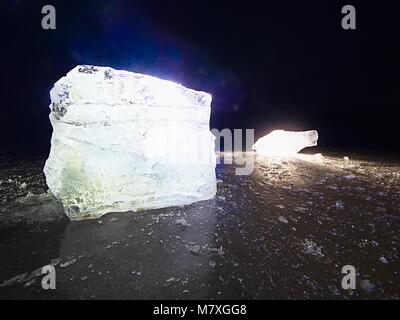 Shining faltige Oberfläche gebrochenem Eis, frische eisige Stücke auf flachen frost Boden. Bunte winter Sonnenuntergang. Stockfoto