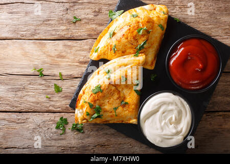 Italienisches Essen: Pizza Calzone mit Fleisch, Gemüse und Käse close-up auf den Tisch. Horizontal oben Ansicht von oben Stockfoto