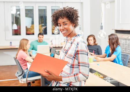 Multikulturelle Frau mit einer Datei vor ihrem Start-up Business Team im Büro Stockfoto