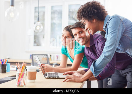 Drei junge Kolleginnen und Kollegen zusammen arbeiten am Laptop im Internet startup Business Stockfoto