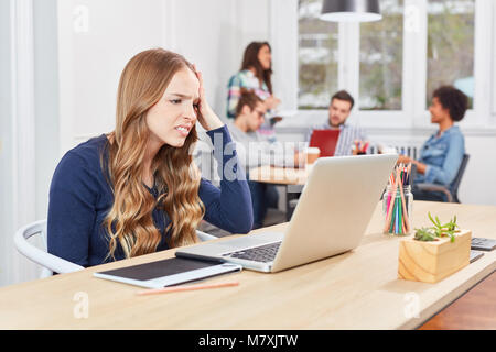 Junge Start-up Unternehmen Frau sitzt auf Laptop Computer in Open-plan Office betont Stockfoto