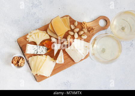 Käseplatte serviert mit weißen Wein, Kekse und Nüsse, Ansicht von oben. Verschiedene Käsesorten Camembert, Brie, Parmesan Blauschimmelkäse, Ziege Stockfoto