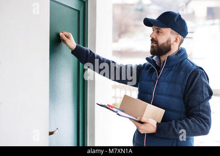 Delivery Man liefern Paketbox an Empfänger-Kurierdienst Konzept. Ein Mann klopft an die Tür. Stockfoto