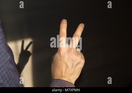 Man wirft zwei Finger auf und zeigt ein Zeichen des Sieges, der Blick von der Rückseite Stockfoto