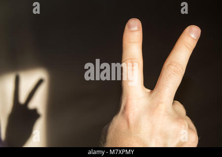 Man wirft zwei Finger auf und zeigt ein Zeichen des Sieges, der Blick von der Rückseite Stockfoto