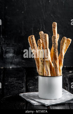 Leckere grissini Grissini. Italienischen Vorspeisen. Holz- dunklen Hintergrund in Metall oldstyle Cup. Stockfoto