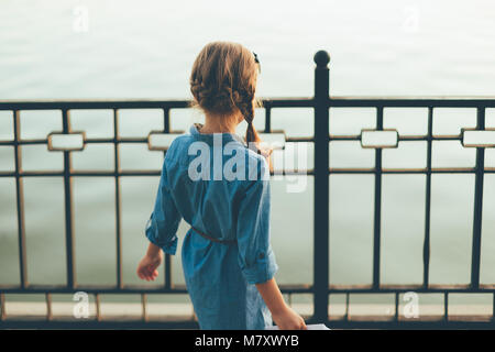 Close-up zurück Blick auf Kinder spielen im Park auf der Suche yo See in Denim Kleid. Mädchen schauen in die Zukunft. Stockfoto