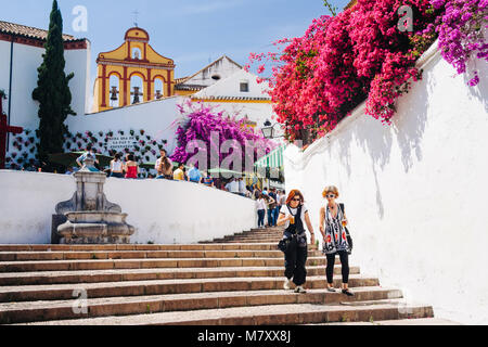 Cordoba, Andalusien, Spanien: Zwei Frauen gehen vorbei Bougainvillea Blumen im Treppenhaus der Cuesta del Bailio Straße mit der Iglesia de los Dolores Stockfoto