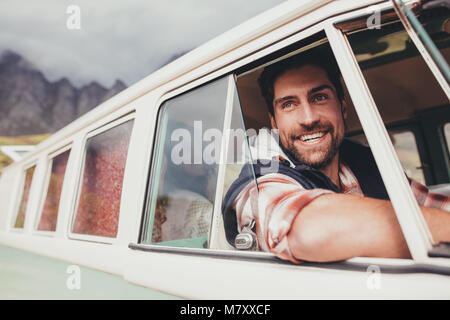 Lächelnder Mann, der einen Van und außerhalb. Stattlichen kaukasischen Mann auf einen Road Trip mit Freunden von einem alten minivan reisen. Stockfoto