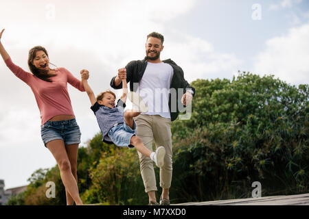 Glückliches Paar in Spielerische im Freien genießen Sie mit Ihrem Kind. Freundliche Familie auf Urlaub genießen im Freien. Stockfoto