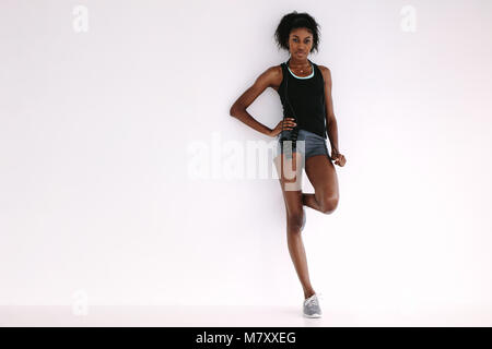 Fit und Gesund afrikanische Frau, die von einem weißen Wand mit Springseil. Die volle Länge der Sportlerin Ausruhen nach Training. Stockfoto