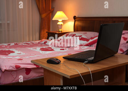 Laptop ist auf dem Nachttisch im Schlafzimmer mit Nachtlicht, niemand in Stockfoto