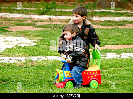 Zwei kleine Jungen mit Motorrad Jacken spielen mit Spielzeug-LKW Stockfoto