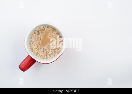 Blick von oben auf die schaumigen Milch Kaffee oder Milch Kaffee in einer Tasse Rot auf weißem Hintergrund Stockfoto