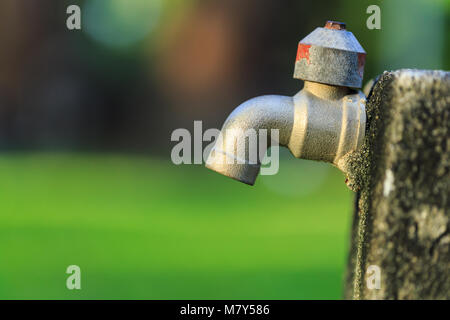 Close up alt draußen Wasserhahn ohne Wasser im Garten auf grünem Hintergrund verschwimmen Stockfoto