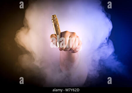 Mann hält vaping Gerät in Farbe Rauch Stockfoto