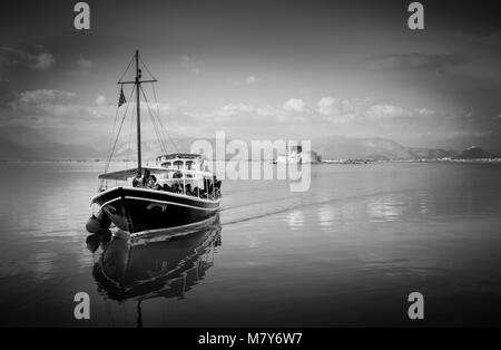 Nafplio, Bourtzi, Griechenland - 27 Dezember, 2015: Boote mit Touristen, Segeln im ruhigen Gewässer des Argolischen Golf, Griechenland. Sonnenstrahlen reflektieren über Blau Grün Stockfoto