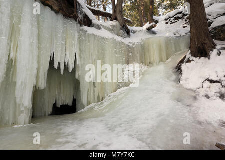 Eben Eishöhlen in Michigan's Upper Peninsula über einen Felsvorsprung, wie ein Wasserfall, Erstellen von gemusterten Vorhängen, Eis in der Nähe von Mühlbach Kreuzung Michigan. Stockfoto