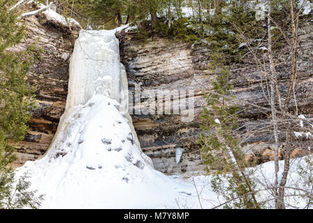 Munising fällt, ein Wasserfall in Munising Michigan solide im Winter friert, von Basalt und Sandsteinfelsen umgeben. Stockfoto