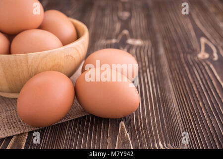 Schließen Sie herauf frische Eier in der Schale auf braunem Holz- Board Stockfoto